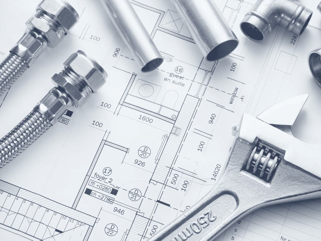 Copper pipe fittings and a wrench on plumbing drawings